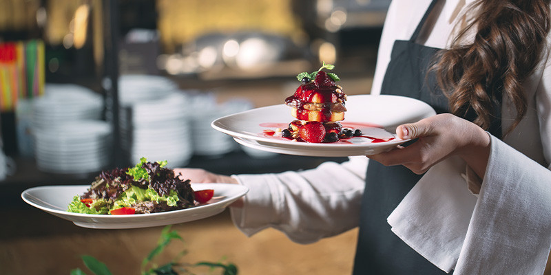 garçonete levando os pratos para os clientes em um restaurante