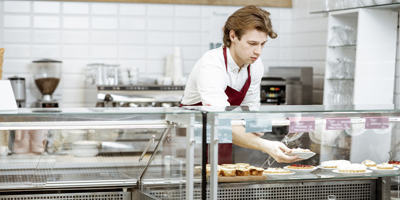 homem arrumando a vitrine de uma cafeteria